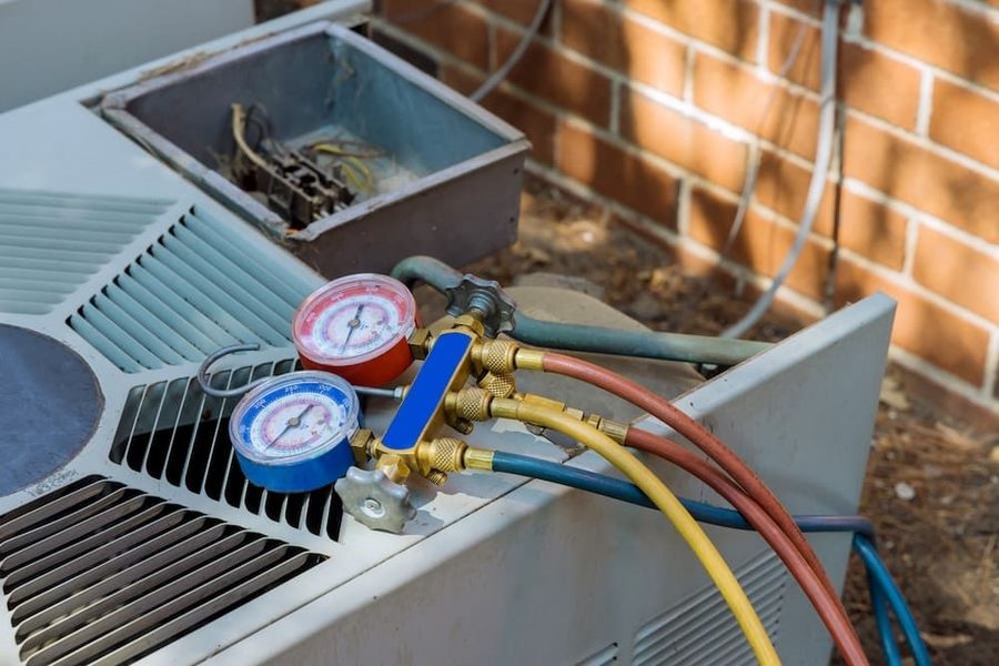 Outdoor air conditioning unit with maintenance tools on top of it. Refrigerant levels are being checked during a maintenance visit.