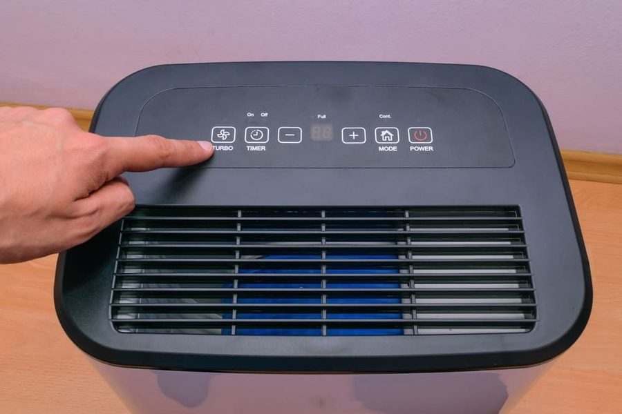 A homeowner changing the settings on a dehumidifier
