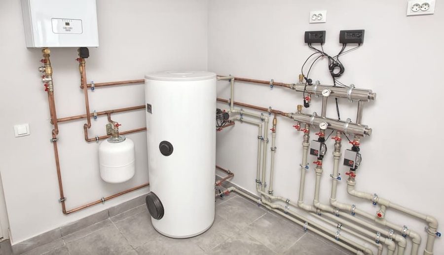 Boiler on basement floor surrounded by pipes on the wall
